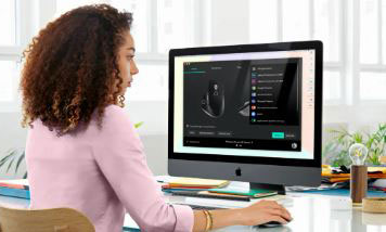 A woman is looking at a monitor with her hand over a mouse